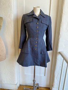 This is a gorgeous Ben Zuckerman New York for Neiman Marcus circa 1950s fitted long jacket. In a charcoal grey nubby silk it has 8 buttons up the front with faux breast and hip pockets. Tailored at the waist and flared at the hips. Fully lined. No size label. Measurements flat are: Underarm to underarm 18" Shoulder to shoulder 15" Sleeve shoulder to cuff 21 Waist 13" Length shoulder to hem 32" Retro Fitted Outerwear With Covered Buttons, Fitted Collared Outerwear With Buttons, Vintage Blazer With Buttons For Workwear, Fitted Collared Blazer With Buttons, Vintage Blazer With Covered Buttons For Work, Fitted Vintage Outerwear With Buttons, Vintage Fall Blazer With Covered Buttons, Fitted Gray Outerwear, Retro Fitted Outerwear With Buttons