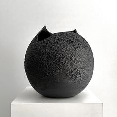 a black vase sitting on top of a white pedestal