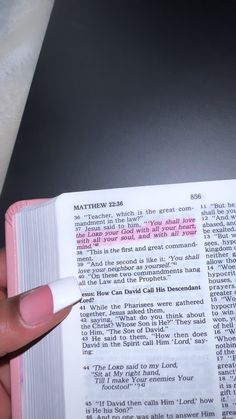 a person is holding an open book with pink writing on it and their thumb pointing at the page