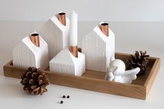 a wooden tray with white and gold decorations on it, including pine cones and candlesticks