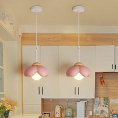 two pink lights hanging over a kitchen island