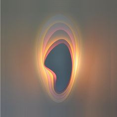 a light that is on the wall in front of a mirror with an abstract design