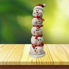 three snowmen stacked on top of each other in front of a wooden table with green blurry background