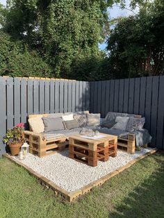 an outdoor seating area made out of pallets and wooden crates with gravel on the ground