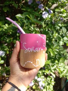 a person holding up a cup with writing on it and a toothbrush in the other hand