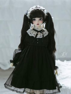 a doll dressed in black and white is standing on a snow covered ground with her hands behind her head