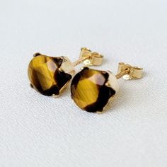 Exude elegance and confidence with these captivating genuine tiger's eye stud earrings. Each earring features a polished tiger's eye gemstone, renowned for its distinctive golden to reddish-brown bands that shimmer in the light, reminiscent of a tiger's eye. Set in a sleek and durable metal base, these earrings provide a secure and comfortable fit for everyday wear. Perfect for adding a touch of natural beauty and sophistication to any outfit, these Tiger's Eye stud earrings are a versatile addi Gold Tiger, Gold Tiger Eye, Gold Bond, Gemstone Stud Earrings, Tigers Eye Gemstone, Gemstone Studs, Tiger's Eye, Gold Set, Gold Filled Jewelry