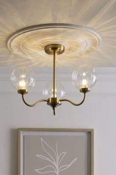 a light fixture with three glass globes hanging from it's center point in a living room