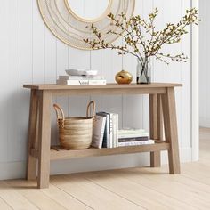 a wooden table with books and baskets on it in front of a white painted wall