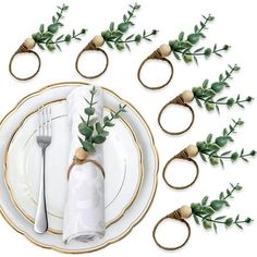 a table setting with napkin rings and greenery