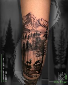 a man's arm with a deer and mountain scene on it