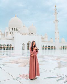 a woman standing in front of a large white building with arches and domes on it