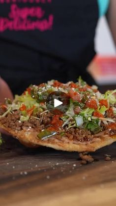 a person holding a pizza on top of a wooden table