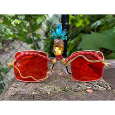 Red retro vintage FINEapple shades.  Colored lens with a wire wrapped rhinestone Pineapple third eye.  Wear to a party, favorite rave or festival....or add to your handmade jewelry collection 💅  Every single pair is unique and one of a kind. These red wire wrapped sunglasses class up any poolside look with sparkly rhinestone pineapple details.  You'll love the way they look on your face, and the compliments you'll receive while wearing them. Trendy Handmade Sunglasses For Party, Trendy Handmade Sunglasses For Parties, Bohemian Sunglasses For Summer Parties, Handmade Sunglasses For Summer Parties, Fun Handmade Sunglasses For Summer, Summer Gift Sunglasses With Glass Material, Handmade Fun Summer Sunglasses, Handmade Sunglasses For Summer Gift, Fun Handmade Sunglasses For Parties