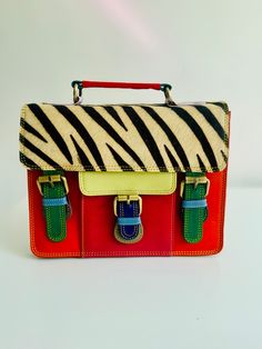 Make a bold statement with our Sustainable Statement Piece: Recycled Leather Crossbody Satchel Bag. This unique bag, handcrafted from colourful recycled leather, is a perfect way to add a touch of personality to your outfit.  Each bag is one-of-a-kind, a beautiful testament to artisanal creation. Makes a perfect gift for any occasion! Birthdays, Mother's Day, Christmas, graduations, or just because - this versatile clutch is sure to be cherished. 🌟 Spacious and functional: Featuring multiple compartments, including zipped pockets, internal pockets, and a handy external pocket on the back, this clutch keeps you organised on-the-go. 🌟 Carry it your way:  With a comfortable carry handle and a detachable crossbody strap, you can choose how you want to wear it. 🌟 Sustainable style: Made with Trendy Multicolor Leather Satchel, Colorful Rectangular Leather Shoulder Bag, Multicolor Top Handle Satchel For Daily Use, Multicolor Satchel For Everyday Use, Multicolor Satchel With Detachable Strap For School, Vintage Multicolor Satchel With Leather Handles, Rectangular Multicolor Satchel For School, Vintage Multicolor Everyday Satchel, Multicolor Retro Satchel For Everyday Use