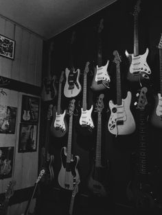 a room filled with lots of guitars hanging on the wall and guitar heads in black and white