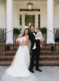 a man in a tuxedo holding two small children and posing for a photo