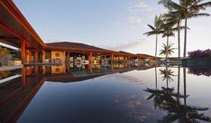 an outdoor swimming pool with lounge chairs and palm trees in the background at sunset or dawn