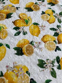 a white table cloth with yellow lemons and leaves on it's surface, covered in water droplets