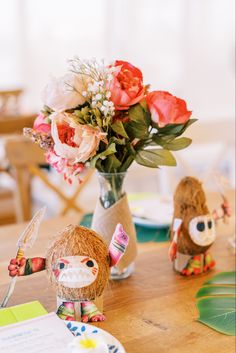 a wooden table topped with vases filled with flowers next to small figurines