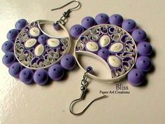 two purple and white earrings are sitting on a table with silver earwires in the shape of circles