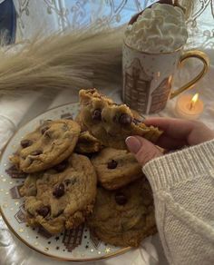 chocolate chip cookies on a plate next to a coffee cup and teacup with marshmallows