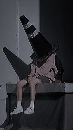 a person sitting on a ledge with a hat on top of their head and one leg in the air