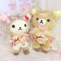 two teddy bears sitting next to each other on a white sheet with pink flowers in the background