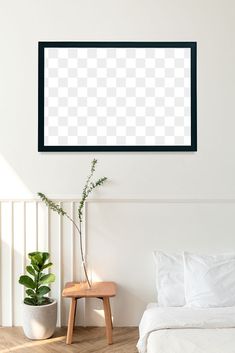 a white bed sitting next to a wooden table with a potted plant on top of it