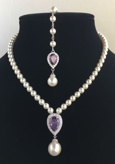 Classic clear cubic zirconia teardrop and pearls bridal necklace in rhodium plated brass setting. This gorgeous necklace features a large teardrop pendant with pear cut purple amethyst cubic zirconia center surrounded by tiny round zirconia crystals with a dangling 12mm swarovski pearl drop. This pendant is strung in a row of Swarovski pearls. Length of the necklace is 16 inches and comes with 2 inches adjustable extender and lobster clasp. Necklace is also available with a 7 inch matching backd Backdrop Necklace Wedding, Crystal Wedding Jewelry, Backdrops Necklace, Bridal Pearl Necklace, Cubic Zirconia Necklace, Pearl Jewelry Wedding, Purple Pearl, Teardrop Necklace, Crystal Wedding