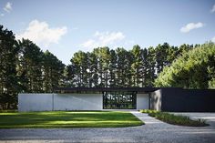 a modern house in the middle of a wooded area with grass and trees around it