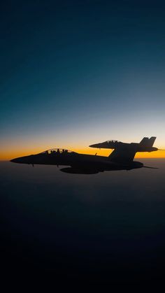 an airplane flying in the sky at sunset