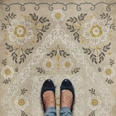 a person standing in front of a rug with flowers on it and one foot up