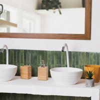 two white bowls sitting on top of a sink under a mirror