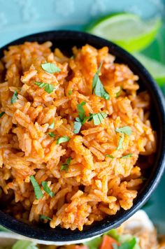 mexican rice in a black bowl with cilantro and lime garnishes