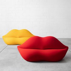 two different colored couches sitting next to each other on cement floor with white brick wall in background