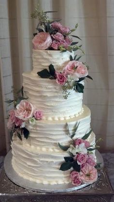 a white wedding cake with pink flowers and greenery