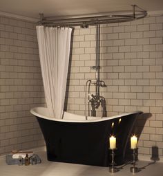 a bath tub sitting next to two candles in a bathroom with white tiles on the walls