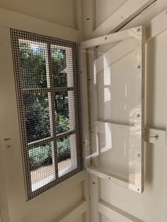 an open window in the corner of a room next to a wall with mesh coverings on it