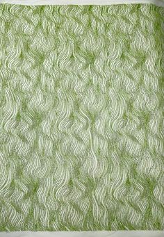 the green and white pattern is made from yarn on top of a piece of cloth