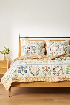 a bed with floral embroidered sheets and pillows