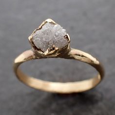 a gold ring with a rough diamond in it's center on a black surface