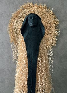 a sculpture made out of straw with a black face