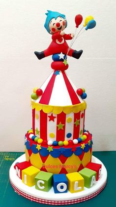 a clown riding on top of a colorful cake