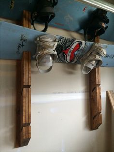 there is a pair of skis on the top of a snowboard rack with shoes hanging from it