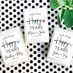 three personalized tea bags sitting on top of a black and white tablecloth with polka dots