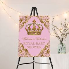 a pink and gold baby shower sign with a tiara on it's head