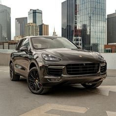 a black porsche cayen is parked in front of some tall buildings and skyscrapers