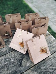 small brown paper bags with dried plants on them sitting on a wooden table in the grass