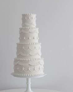 a three tiered white wedding cake sitting on top of a table